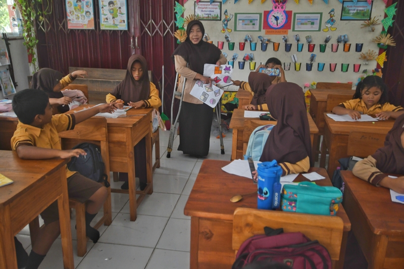 Inspiratif! Guru di Grobogan Ini Semangat Mengajar Meskipun Berdiri dengan Dua Tongkat