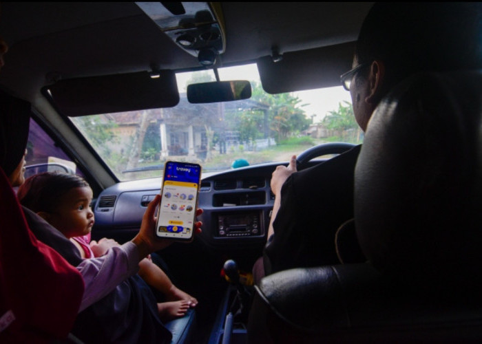 Seorang anak menunjukkan aplikasi Travoy kepada ayahnya di perbatasan Kabupaten Grobogan - Sragen, Jawa Tengah, Rabu (15/4/2026). PT Jasa Marga (Persero) Tbk meluncurkan aplikasi Travoy sebagai bagian dari komitmen transformasi layanan digital untuk memudahkan para pengguna jalan tol di Indonesia. (Achmad Fazeri/Disway Jateng)