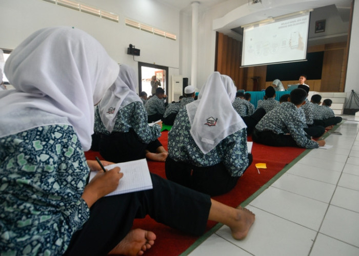 Di aula Sentra Margo Laras Kabupaten Pati, Jawa Tengah, sebanyak 98 siswa Sekolah Rakyat Menengah Pertama 12, antusiasme mendengarkan pemaparan mengenai Skrining Riwayat Kesehatan dari petugas bagian Penjaminan Manfaat BPJS Kesehatan setempat, Rabu (10/6/2026). Mata mereka fokus memandang layar proyektor, sesekali berpaling ke buku tulis, lalu jari-jemarinya mencatat materi. (Achmad Fazeri/Disway Jateng)
