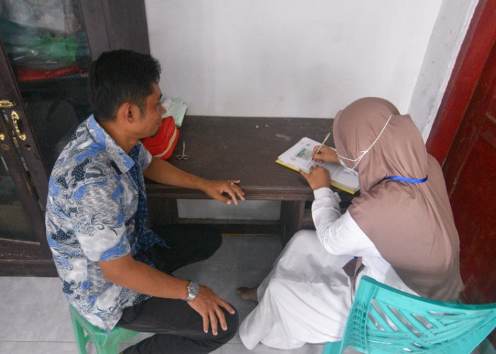 SURAT RUJUKAN: Bidan Polindes Sabuntan, Indah Milasari, membuat surat rujukan pasien lansia, Mamah, yang ditujukan kepada Puskesmas Sapeken di Pulau Sapeken, Kecamatan Sapeken, Kabupaten Sumenep, Jawa Timur, Selasa, 3 Juni 2025. (Achmad Fazeri/Disway Jateng)